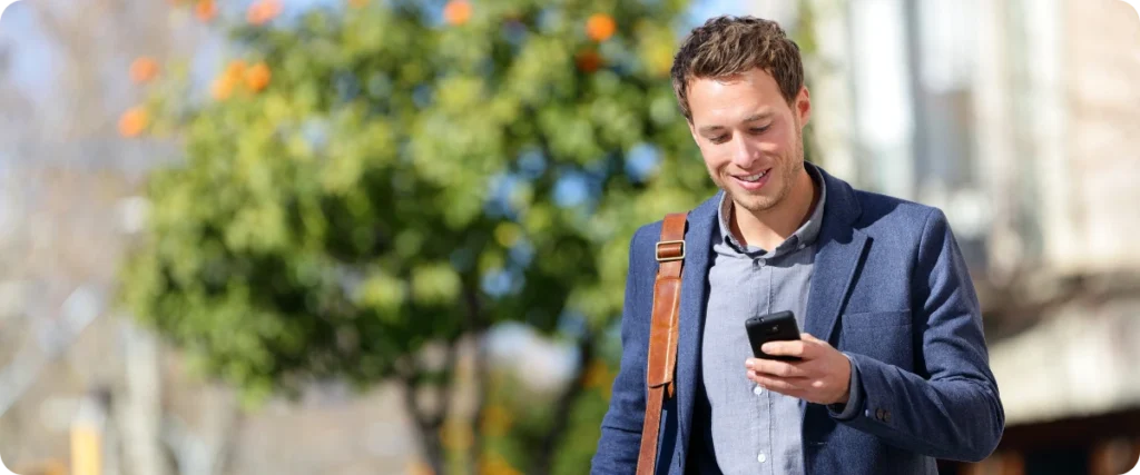A men is looking on his mobile phone on the go